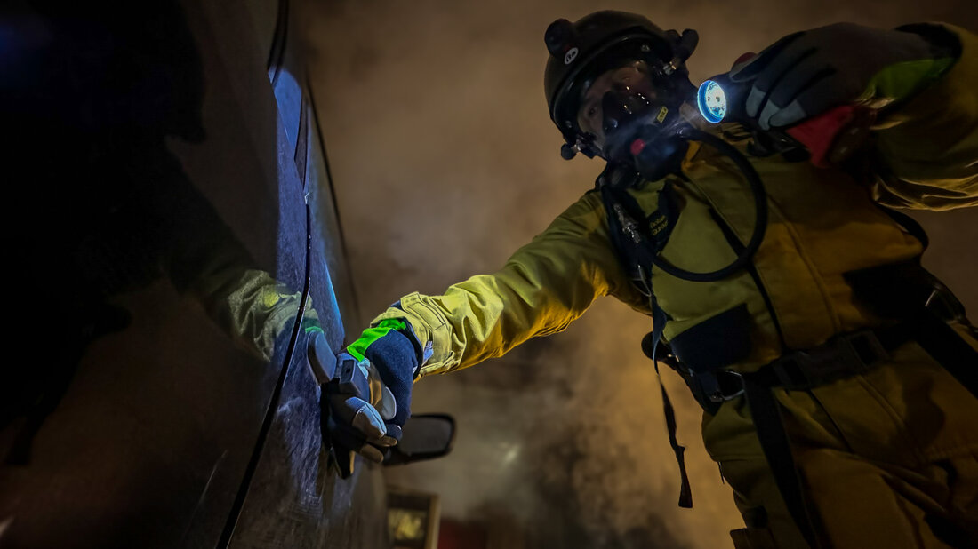 A firefighter tries to open a vehicle in a smoke-filled tunnel.