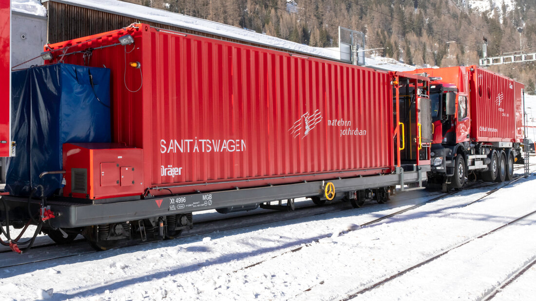 Le véhicule sanitaire est constitué d’un conteneur disposé sur un wagon porte-conteneurs; on aperçoit le lot de bouteilles d’air respirable installé à l’extérieur du conteneur. 