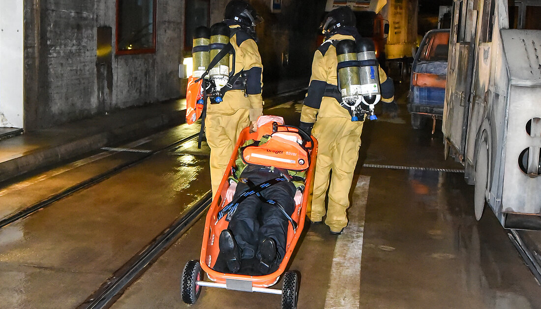 Feuerwehrangehörige nutzen eine Schleifkorbtrage mit Rollen im Tunnel