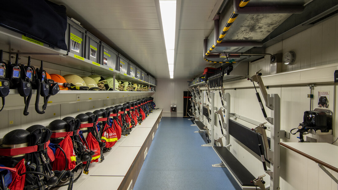 Interior of a rescue vehicle of a fire and rescue train, with equipment for firefighters and holding devices for patient stretchers.