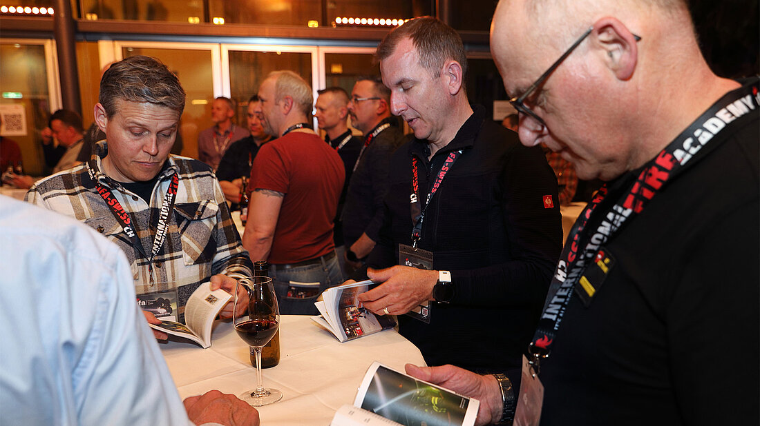 Gäste des Kommandanten-Forums blättern im neuen Fachbuch «Üben am Standort»