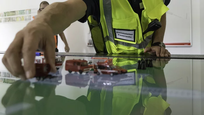 [Translate to French:] Stabsraum für den Lötschberg-Basistunnel mit Besprechungstisch und Funktionswesten über den Stuhllehnen