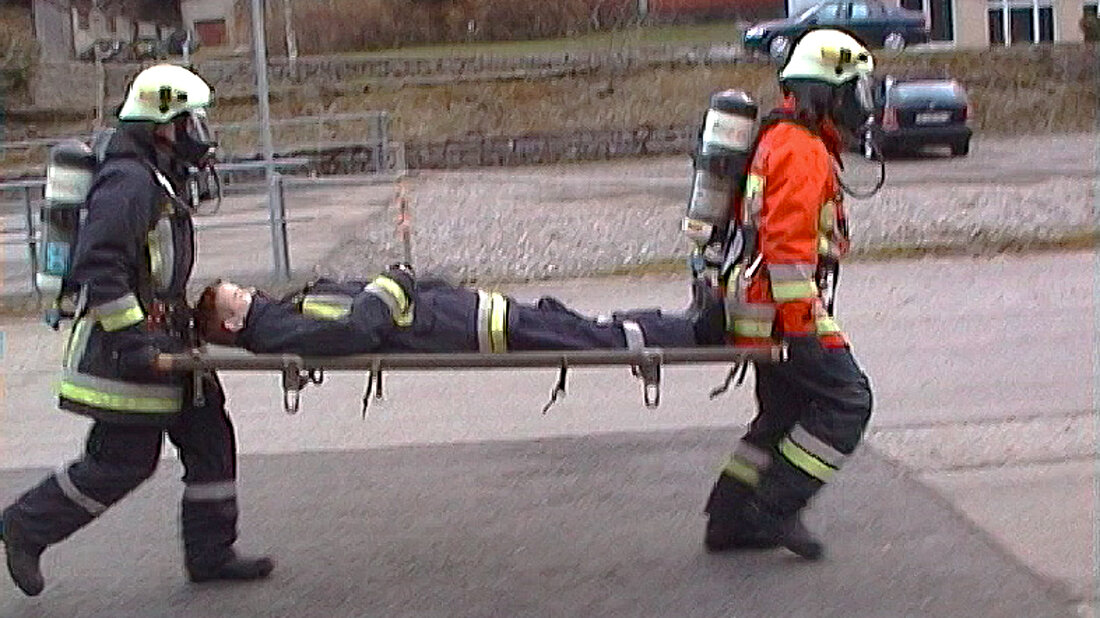 Feuerwehrangehörige transportieren im Laufschritt eine Person auf einer Trage – über lange Strecken keine gute Lösung