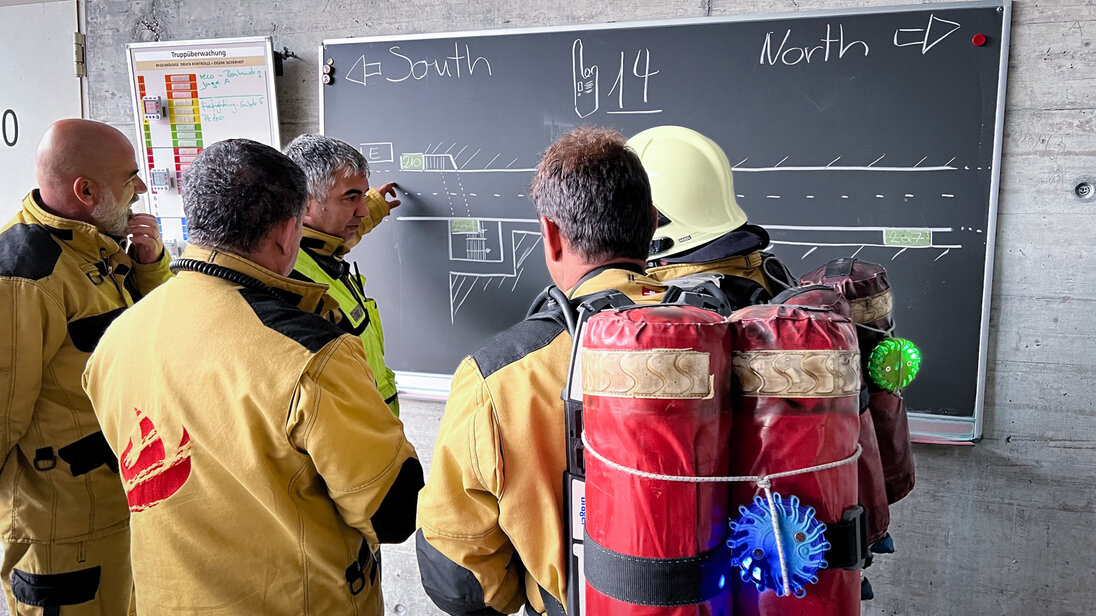 Lagebesprechung der Kursteilnehmer mit einem Instruktor zu einer Übung im Tunnel