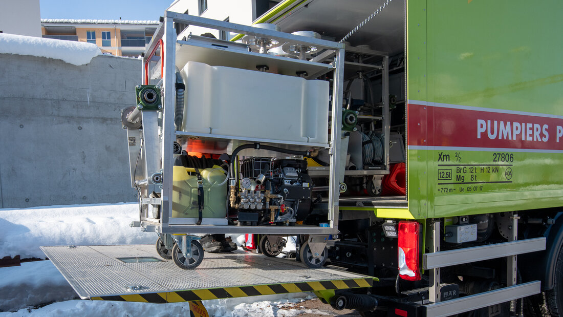 Road-rail vehicle with an opened tail lift platform and a modular cart on it.