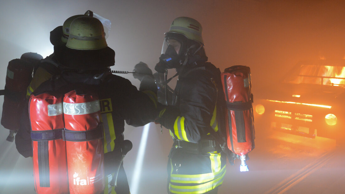 Two firefighters communicate with each other using non-verbal communication during an operational drill