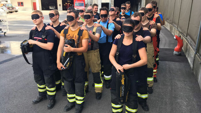 Feuerwehrangehörige mit Augenbinde üben blindes Vertrauen und Kommunikation in schwierigen Situationen