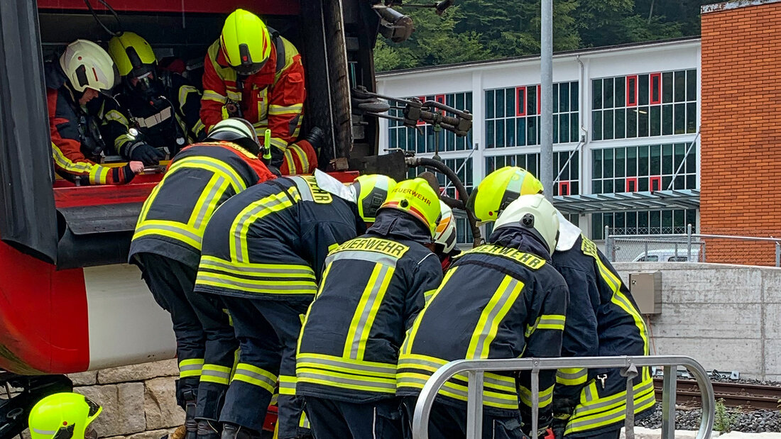 Feuerwehrangehörige üben das Retten einer Person aus einem umgekippten Bahnwagen