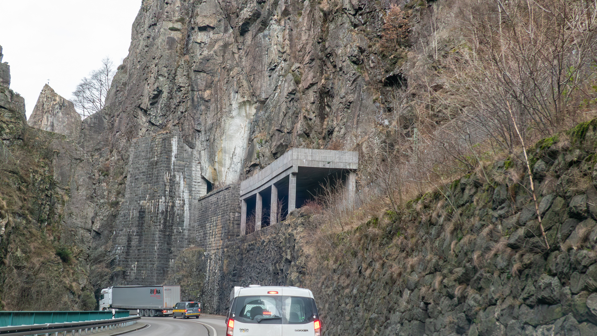 Tunnelportal oberhalb einer Strasse, das direkt in ein Felsmassiv führt